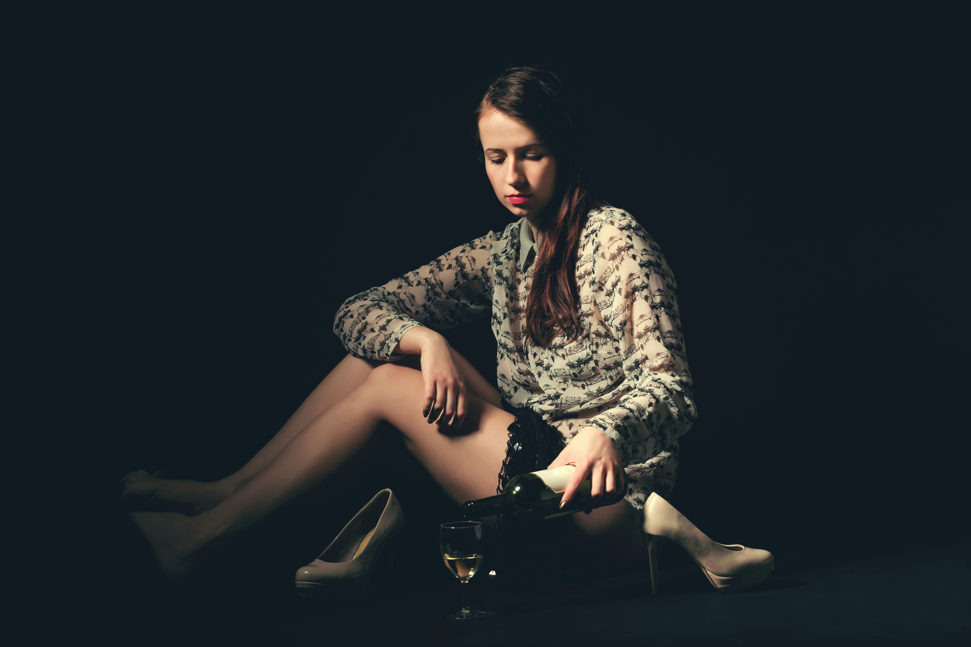 Studio portrait of a beautiful young brunette woman holding a bottle of white wine in retro colors