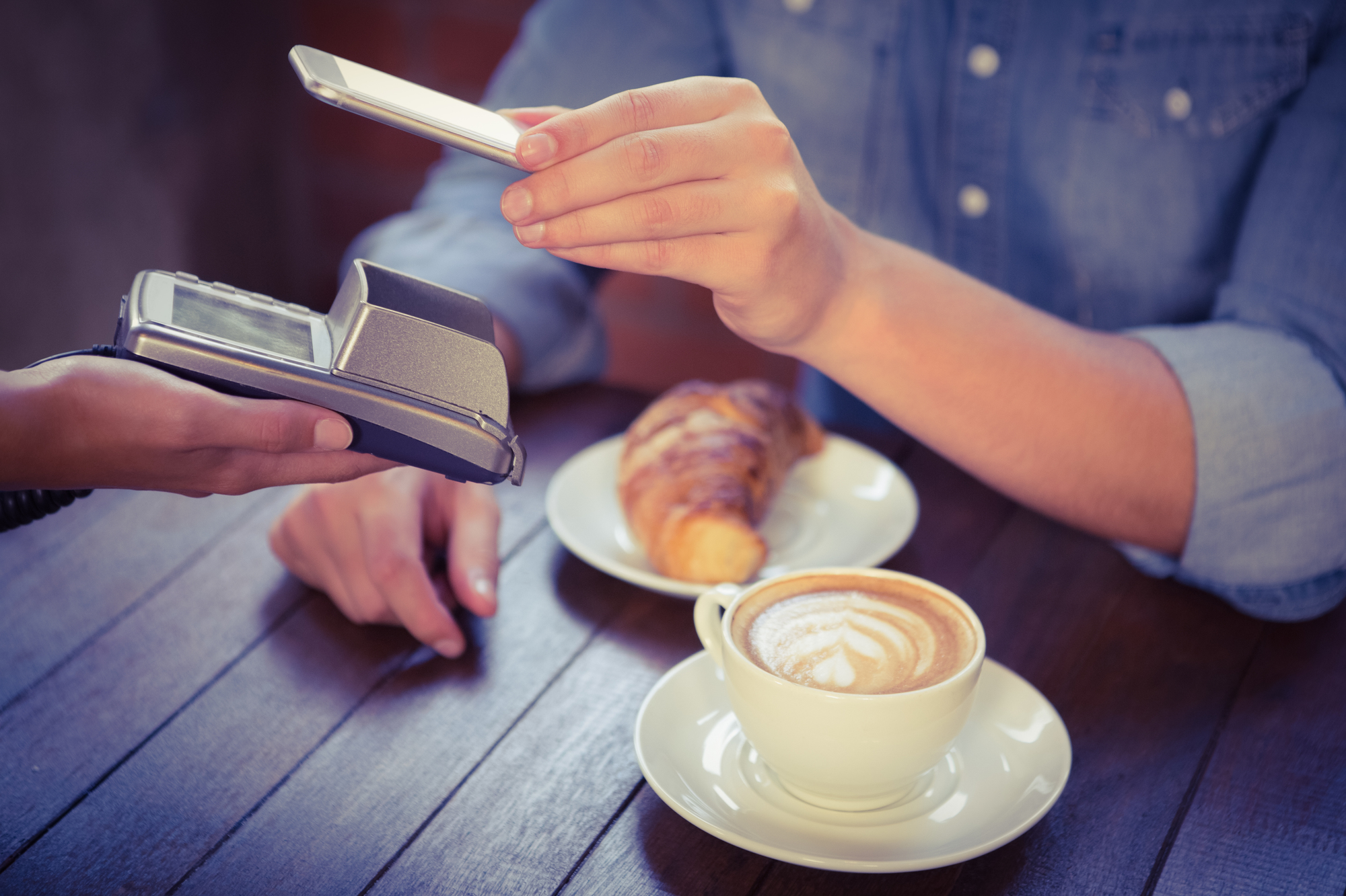 Male customer paying with smartphone at coffee shop
