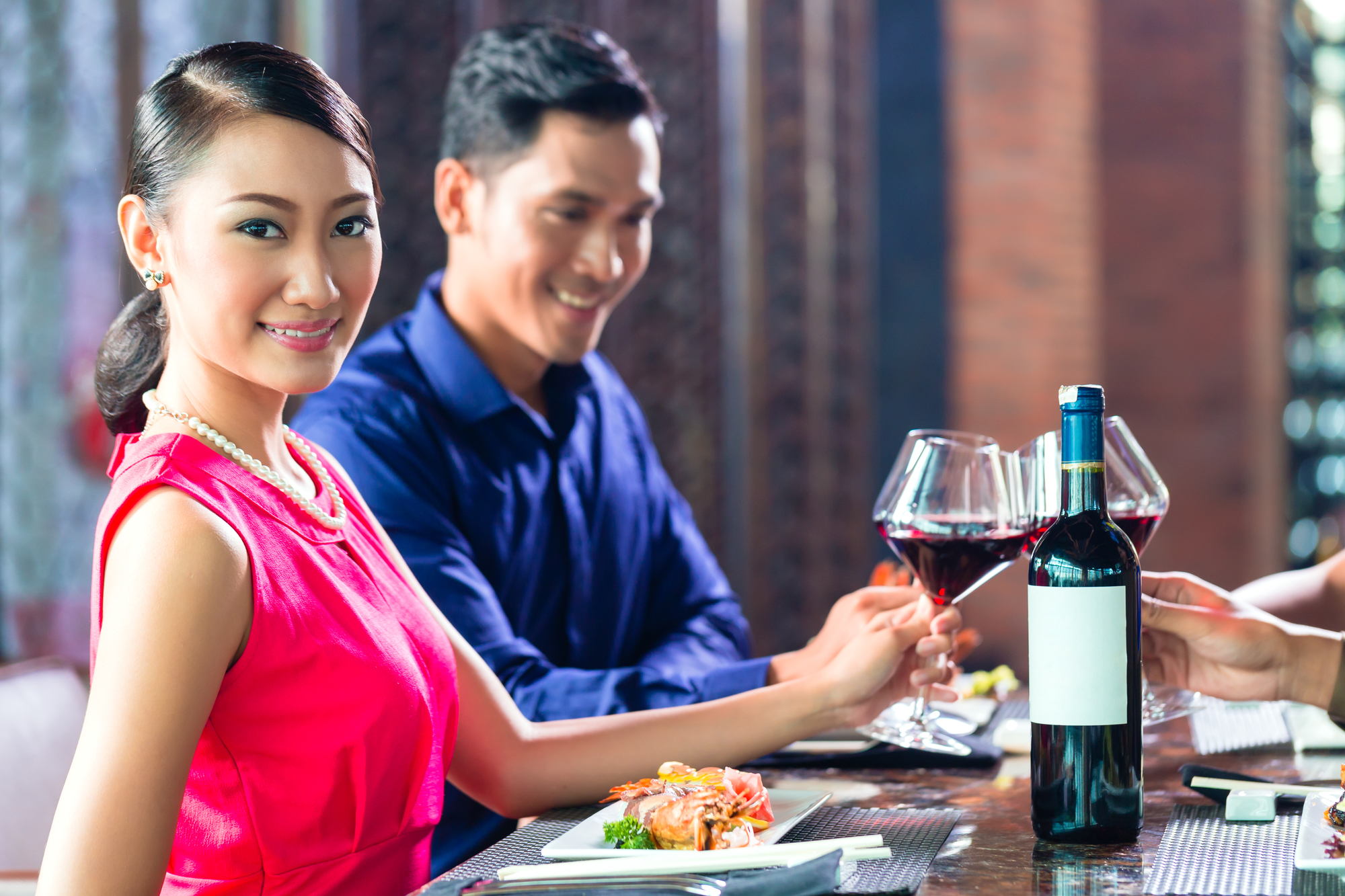 Asian Friends celebrating with red wine in restaurant