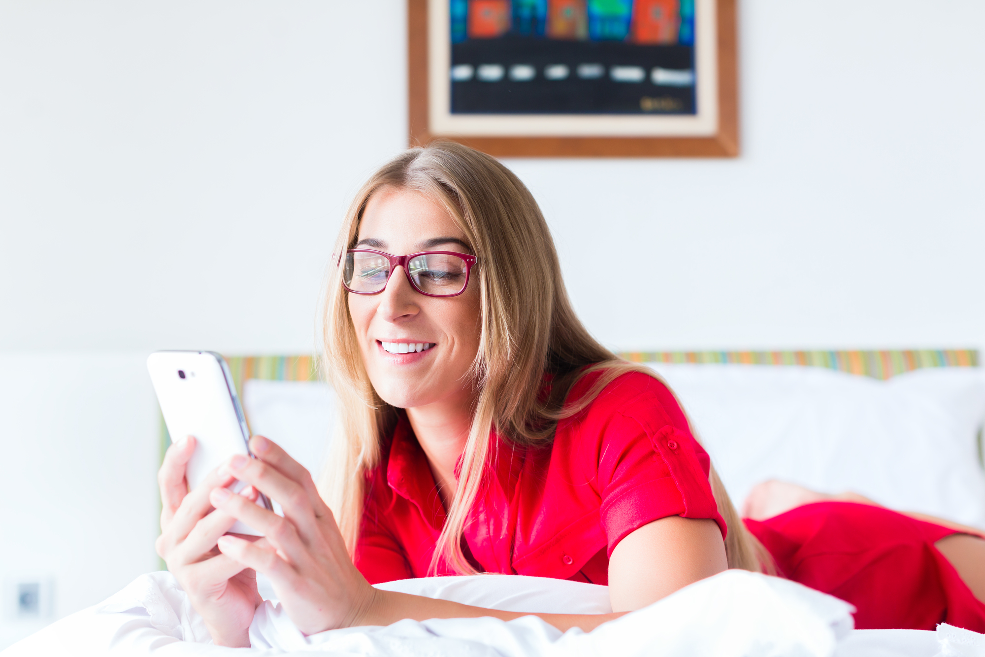 Woman reading Mails on smartphone on bed