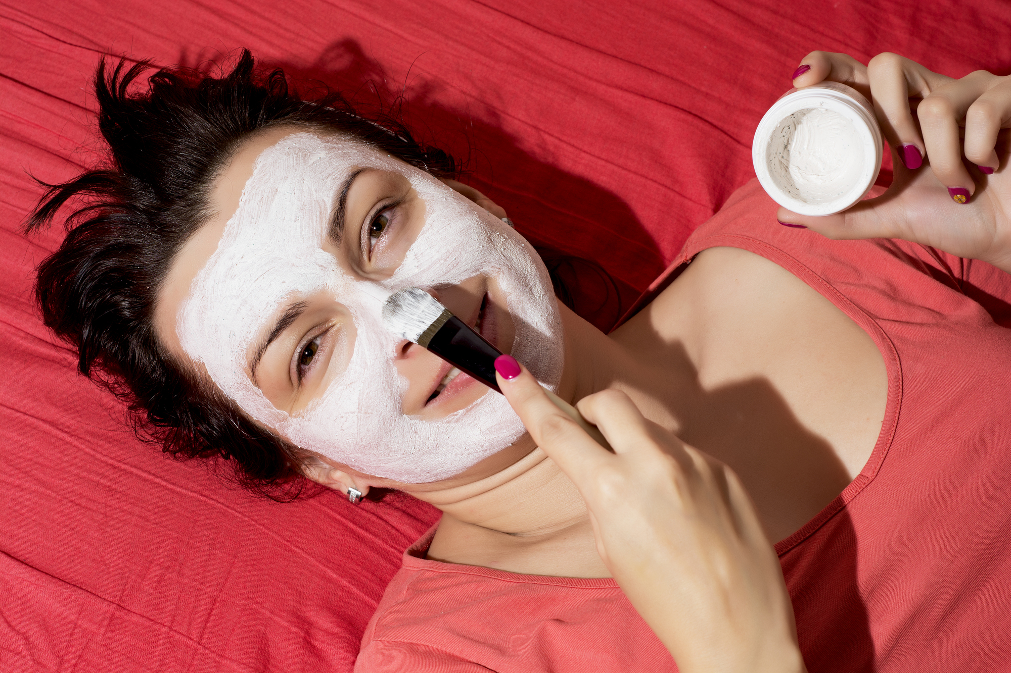 Young caucasian woman having a white smoothing face mask.