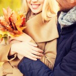 love, relationship, family and people concept - close up of smiling couple with bunch of leaves hugging in autumn park