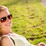Beautiful young woman wearing sunglasses outside in sunny summer nature