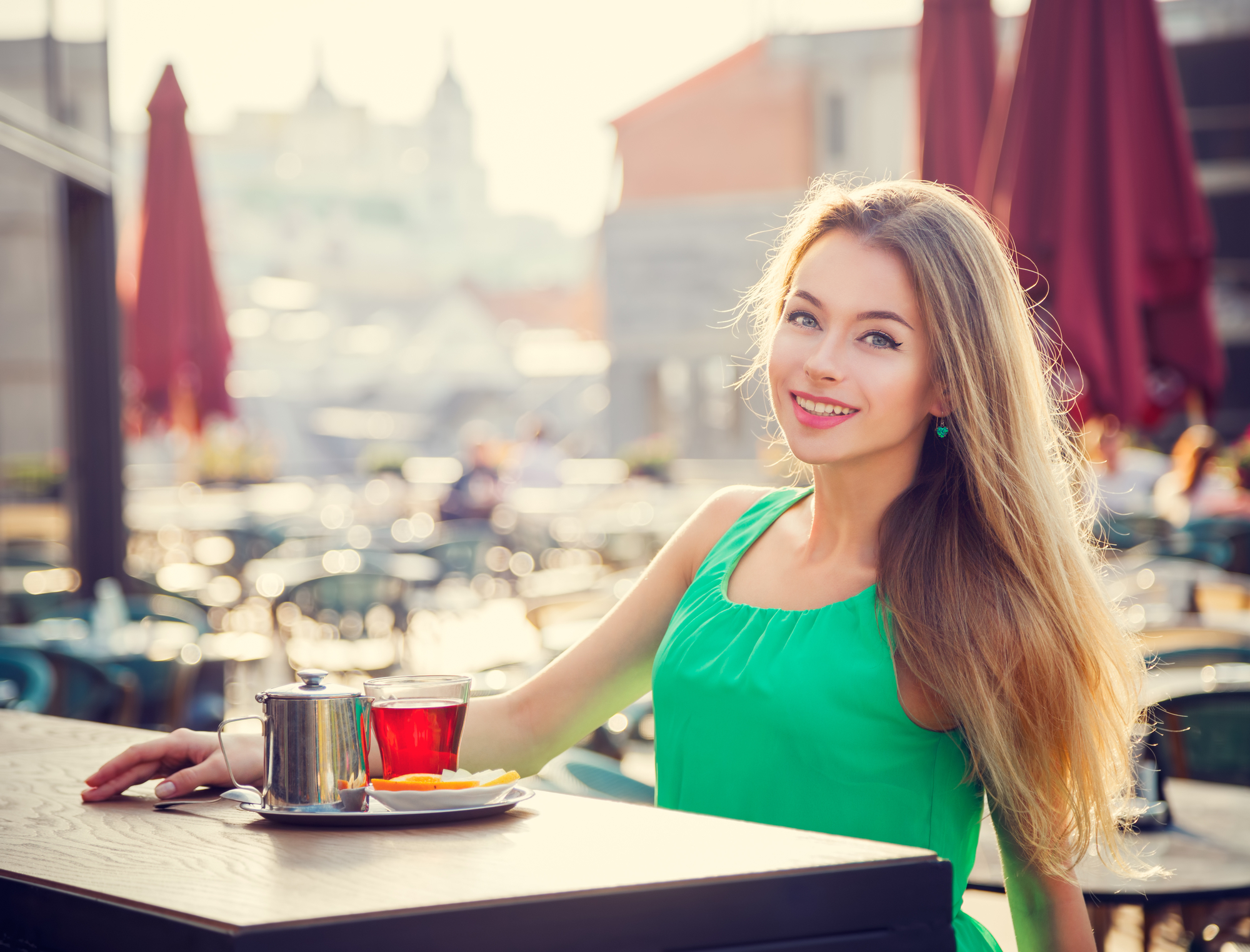 Young Woman Drinking Tea in a Cafe Outdoors. Summer City Background. Shallow Depth of Field. Toned Photo.