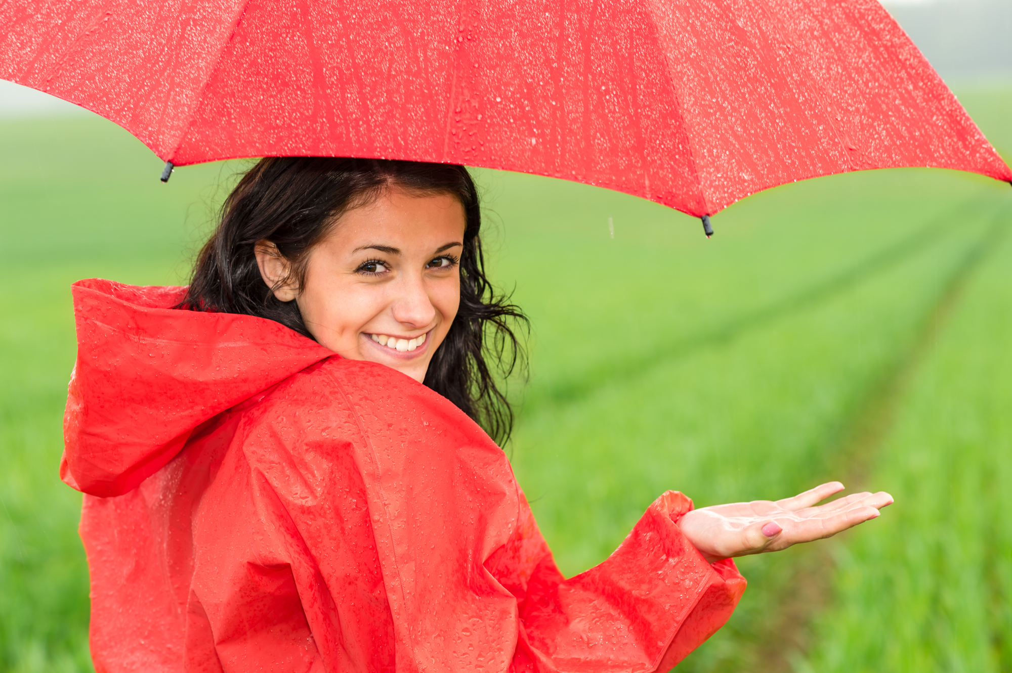 Lively teenager girl in the rain looking at camera