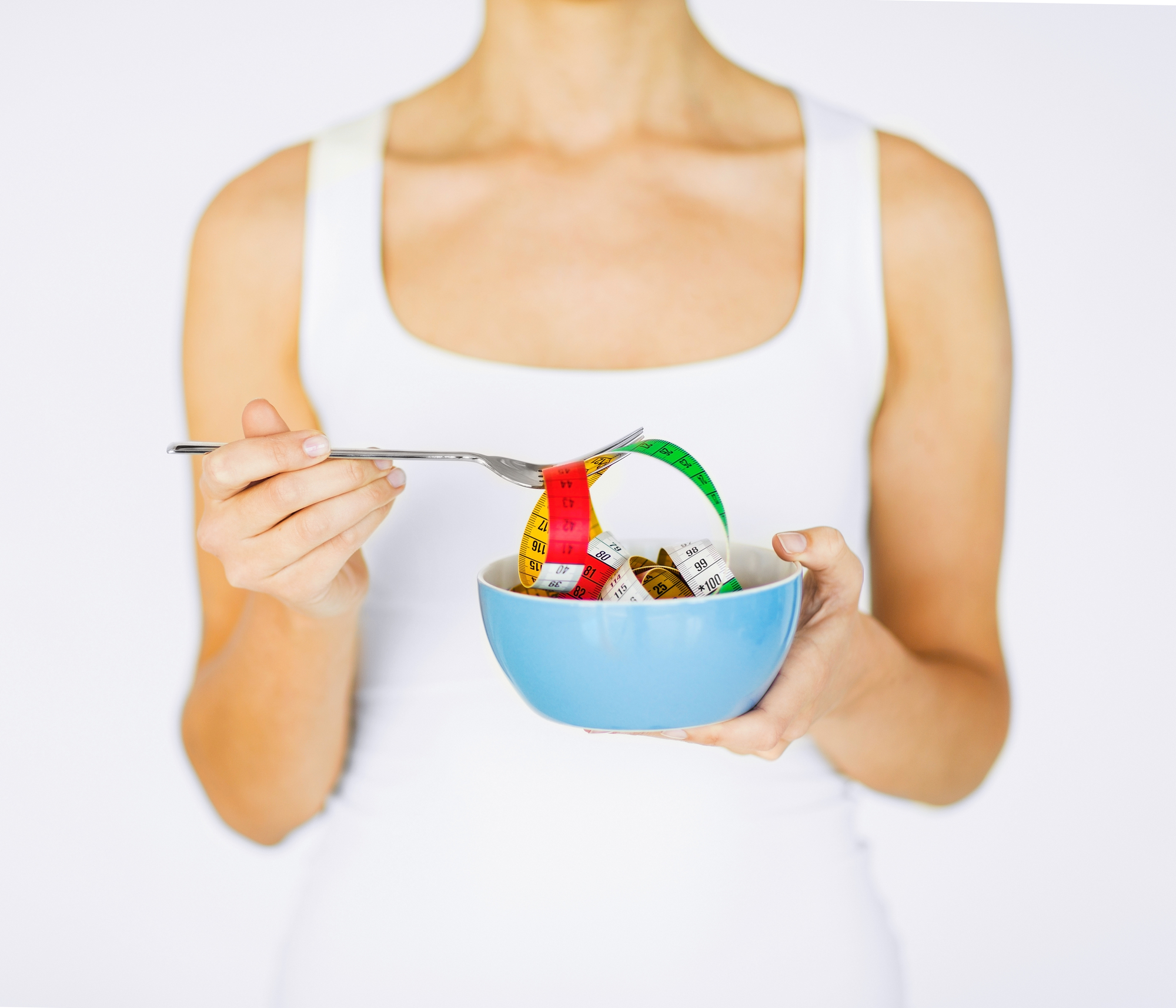 sport and diet concept - woman hands holding bowl with measuring tape