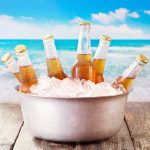 cold bottles of beer in bucket with ice over sea