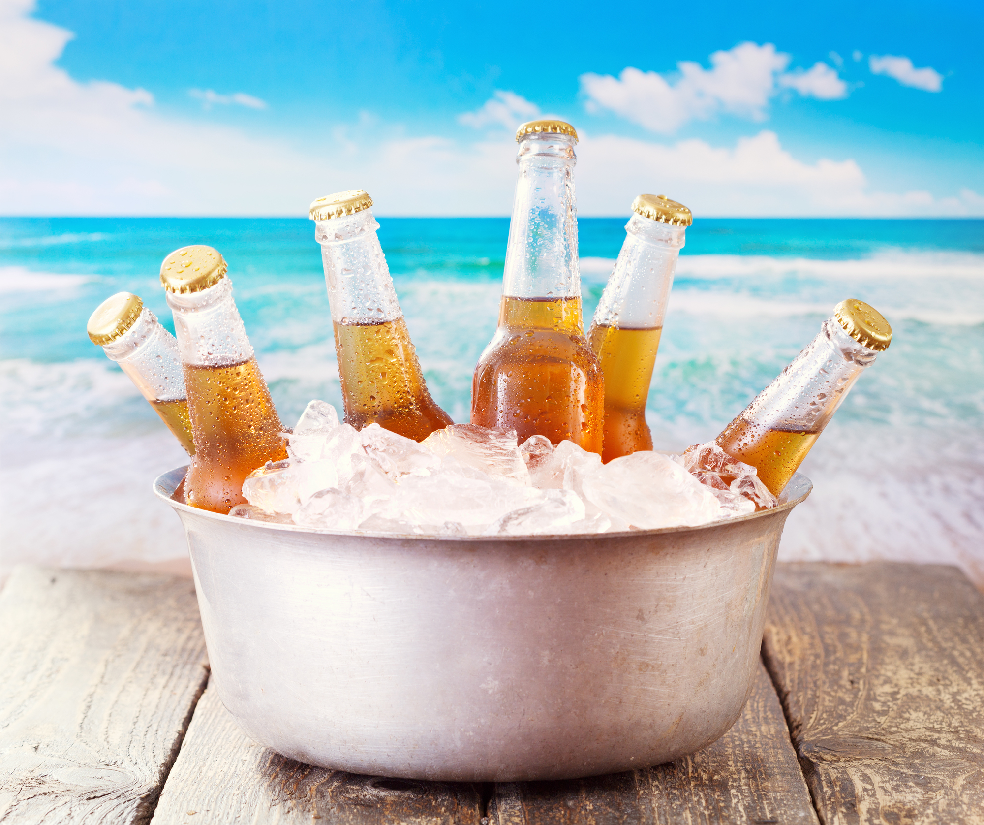 cold bottles of beer in bucket with ice over sea