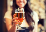 leisure, drinks, degustation, people and holidays concept - close up of smiling woman hand holding glass of draft lager beer